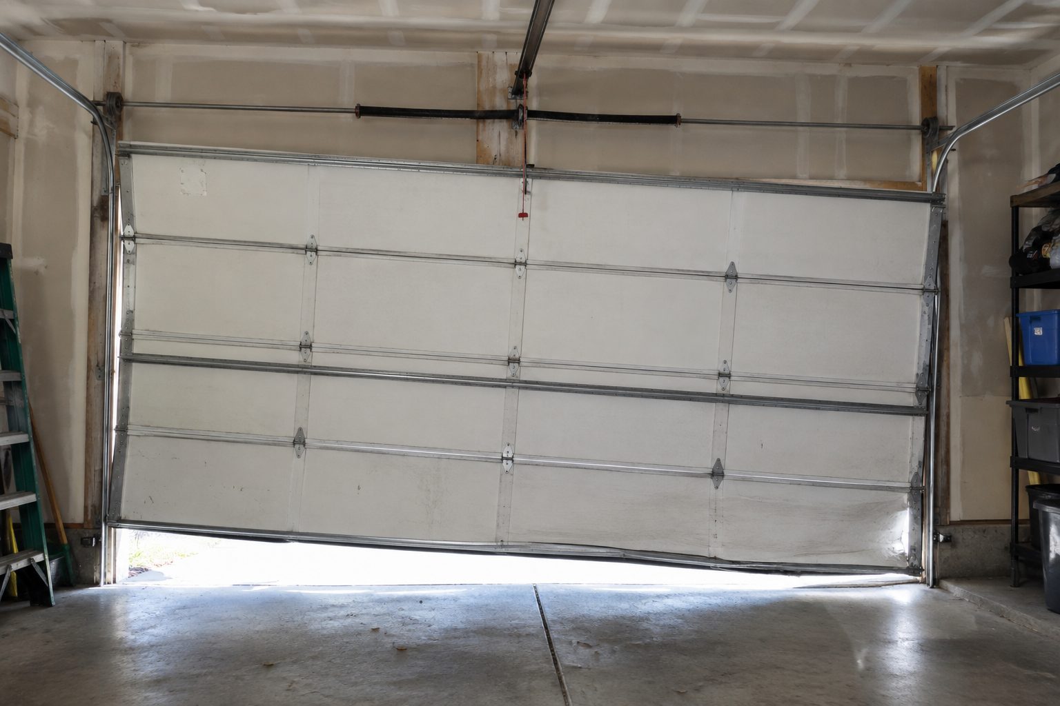White sectional garage door hanging crooked with a roller out of its track
